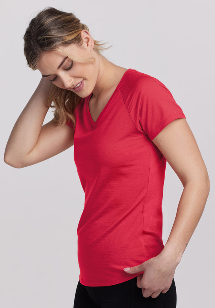 Woman in a Woolx Mia V Neck - Berry Ice Pop, standing sideways and smiling with a hand on her head.