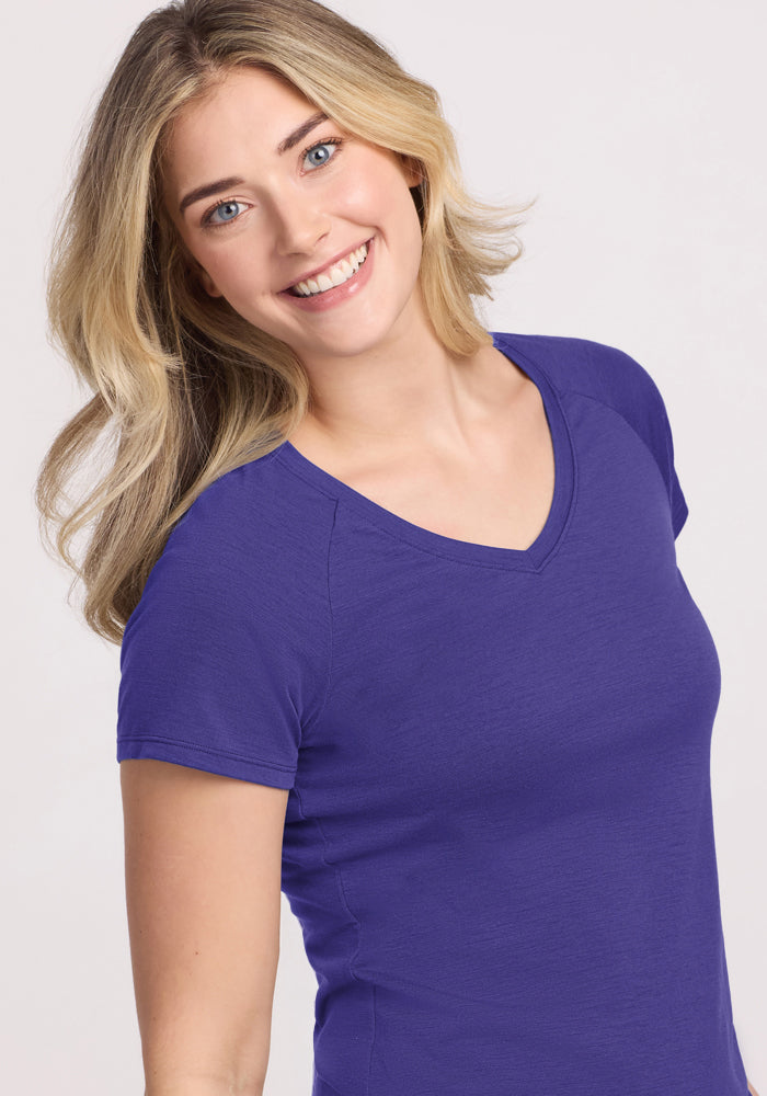 Blonde woman smiles in a Woolx Mia V Neck - Berry Indigo tee, standing against a light background.