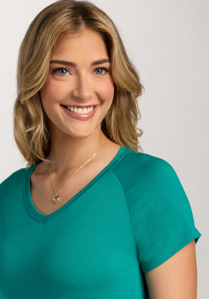 Smiling woman in the Woolx Mia V Neck - Cabana Crush, teal merino wool shirt, with a gold necklace.