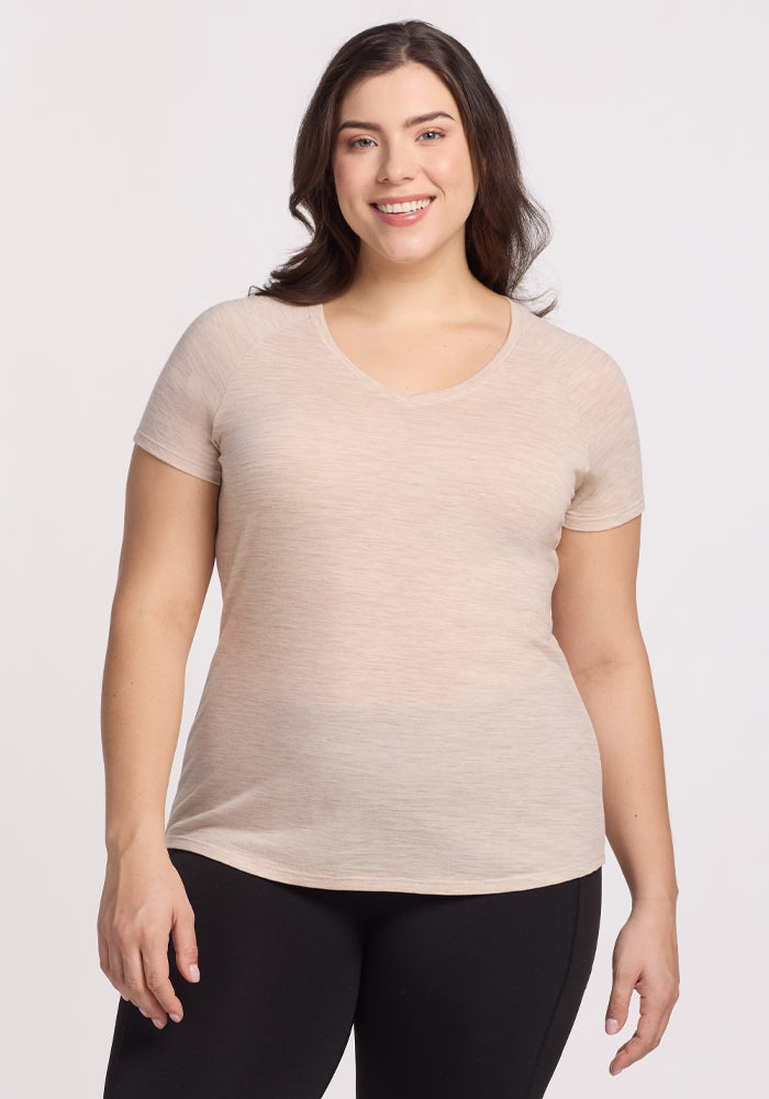 A smiling woman with long dark hair wears the Mia V Neck in Cream Heather by Woolx and black leggings, standing against a plain white background. | Juliana is 5'10", wearing a size XL