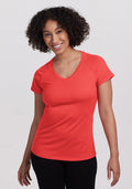 Smiling woman with curly hair wears Woolx Mia V Neck - Hibiscus and black pants, looking at the camera. | Tori is 5'7", wearing a size S