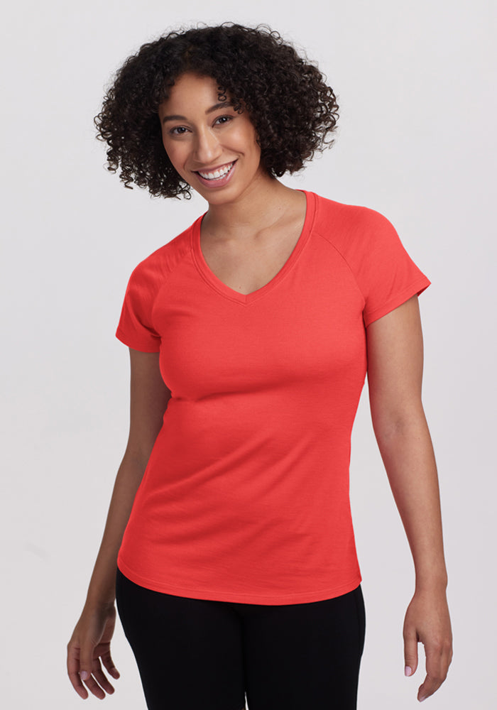 Smiling woman with curly hair wears Woolx Mia V Neck - Hibiscus and black pants, looking at the camera. | Tori is 5'7", wearing a size S