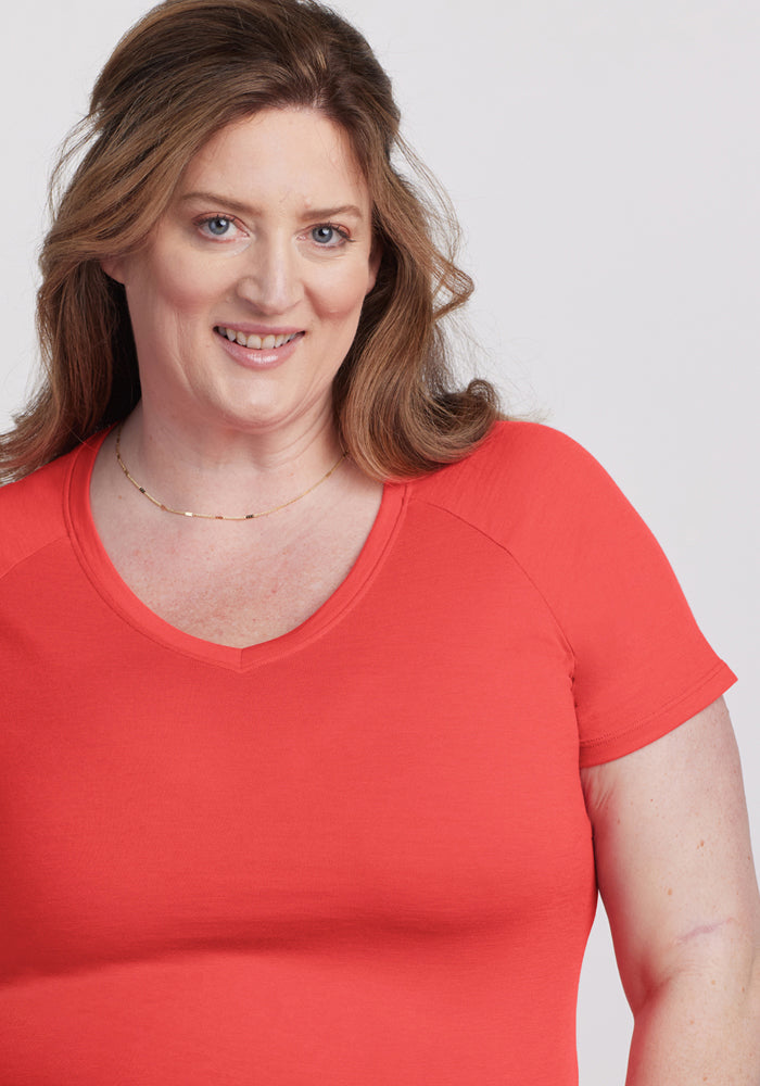 Woman with long brown hair wears the Woolx Mia V Neck - Hibiscus, smiling at the camera against a light background.