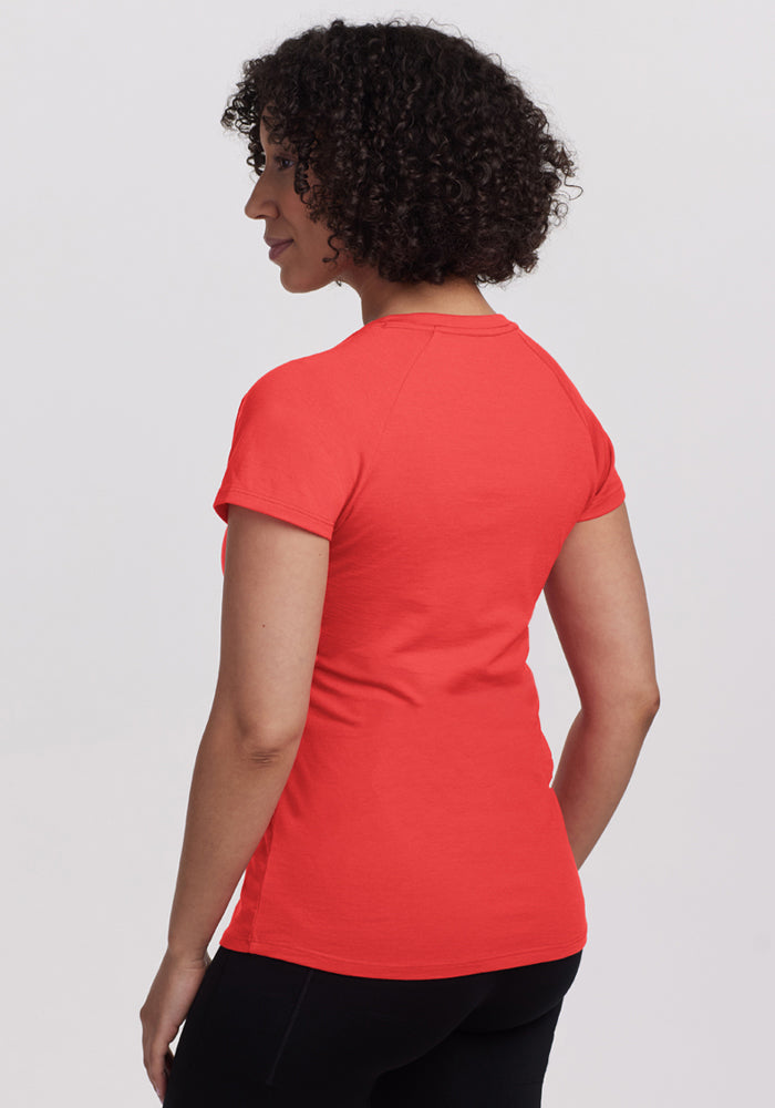 A person with curly hair wears the Woolx Mia V Neck - Hibiscus and black pants, facing away from the camera.