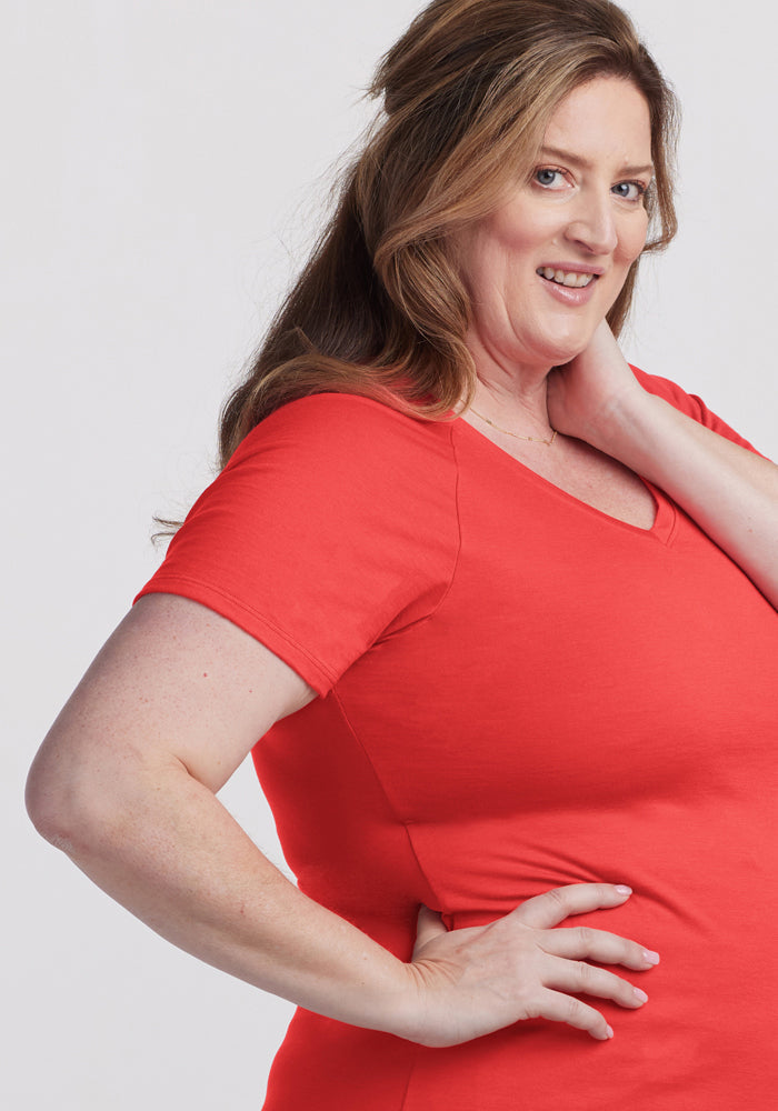 Woman with long brown hair smiles in the Woolx Mia V Neck - Hibiscus, posing with a hand on her hip.