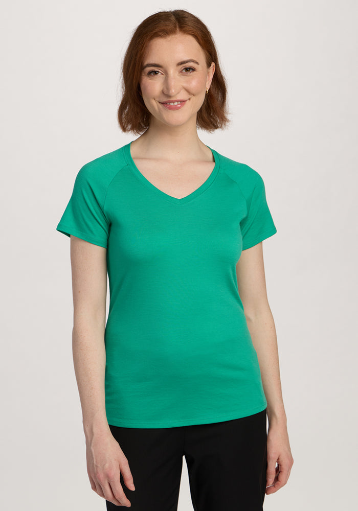 Woman with short brown hair smiles in a Woolx Mia V Neck - Jungle and black pants. | Shea is 5’9”, wearing a size S