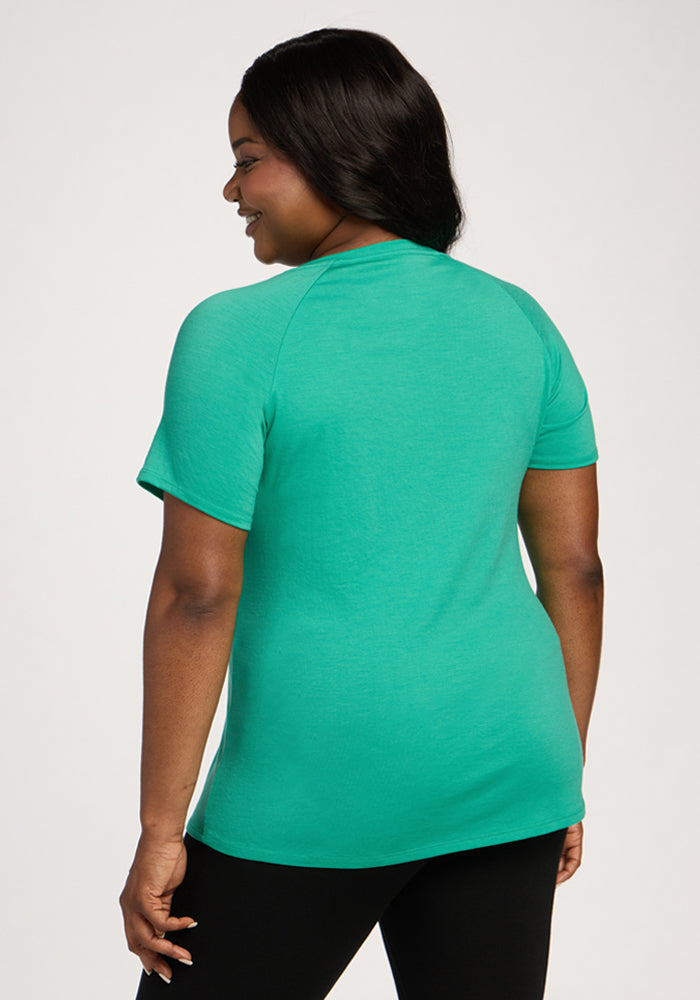 Woman wearing the Woolx Mia V Neck - Jungle tee, shown from the back, standing and smiling in black pants.