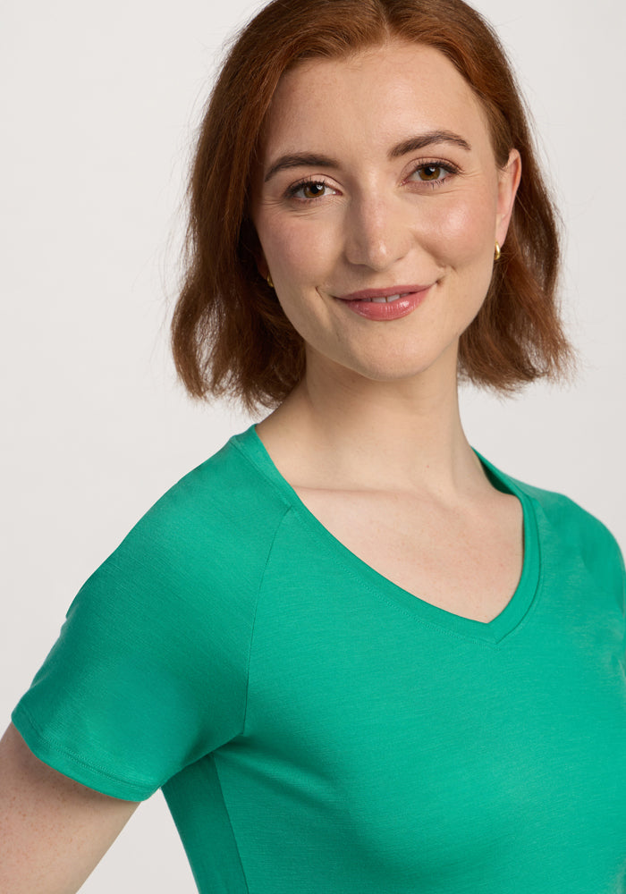 Smiling woman with short auburn hair wears the Woolx Mia V Neck - Jungle, posing against a white background.
