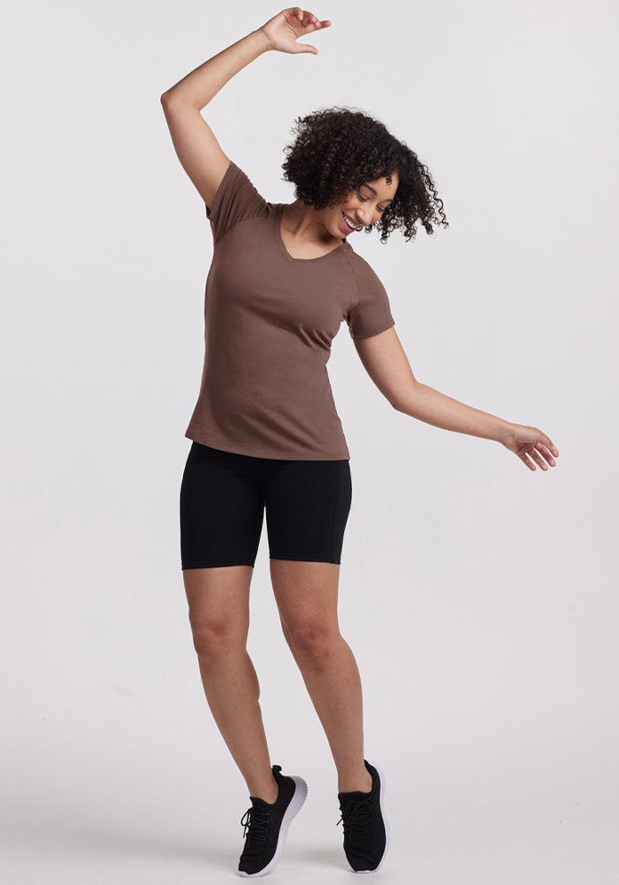 A person in a Woolx Mia V Neck - Peppercorn dances joyfully against a plain white background.