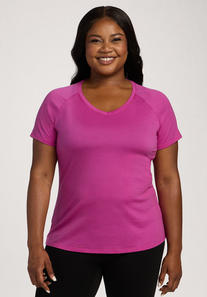 Smiling woman in the Woolx Mia V Neck - Summer Sorbet and black pants against a plain light background. | Sapphire is 5'8", wearing a size XL