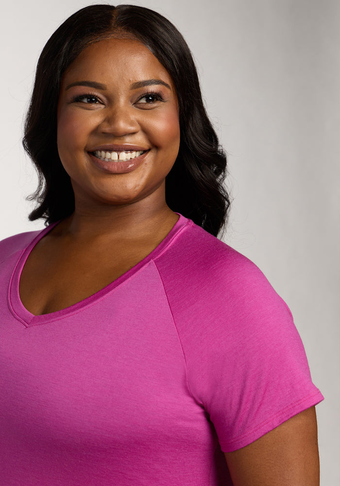 Woman smiling in a Woolx Mia V Neck - Summer Sorbet shirt, with dark wavy hair against a light background.