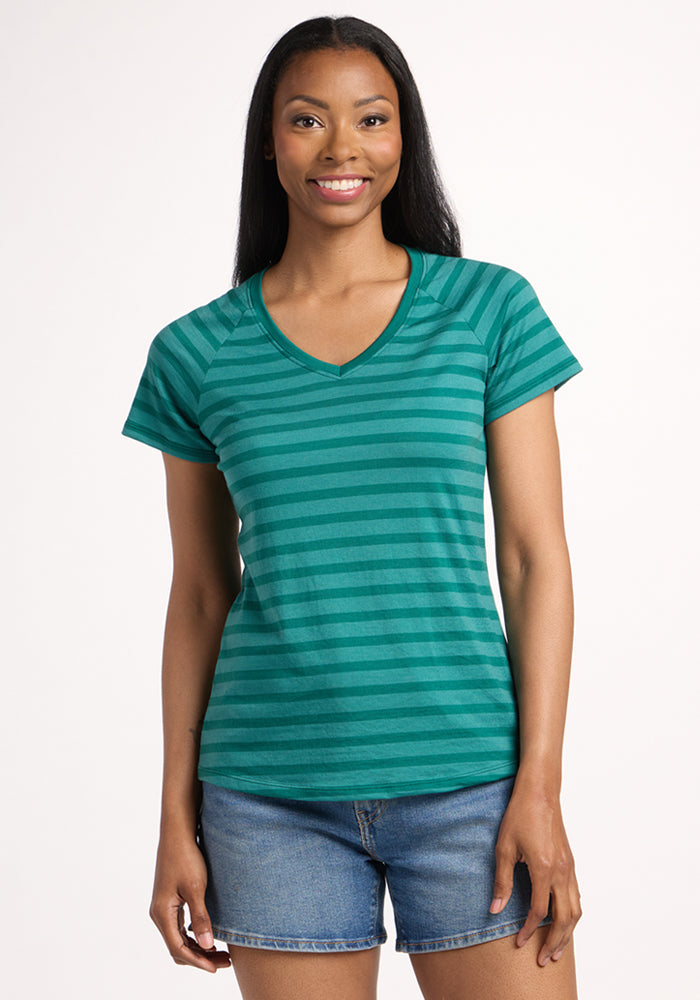 A woman with long dark hair, wearing the Woolx Mia V Neck - Woodland Stripe and denim shorts, smiles against a plain white background. | Jade is 5’10”, wearing a size S