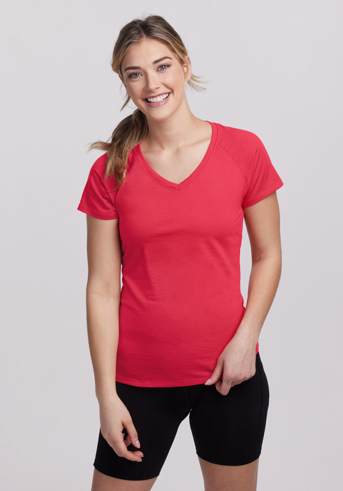 Smiling woman wears the Woolx Mia V Neck in Berry Ice Pop and black shorts against a plain light background. | Ariana is 5'11", wearing a size S