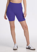 Someone wears Woolx Miley Bike Shorts - Berry Indigo and white sneakers, standing against a plain white background. | Jessica is 5’10”, wearing a size S