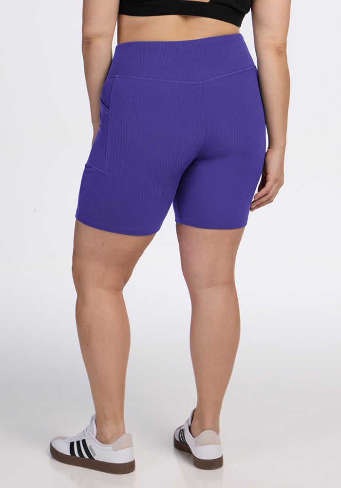 Person in a black top and Woolx Miley Bike Shorts - Berry Indigo, shown from the back on a white background.