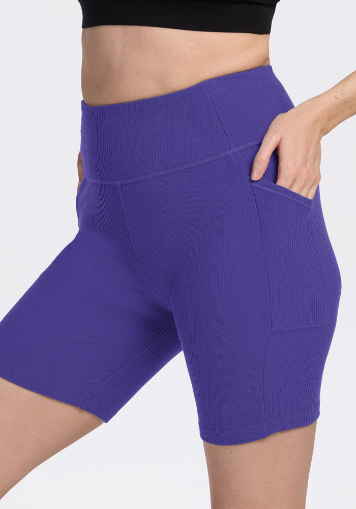 Someone in Woolx Miley Bike Shorts - Berry Indigo with pockets and a black crop top, highlighting stylish workout wear.