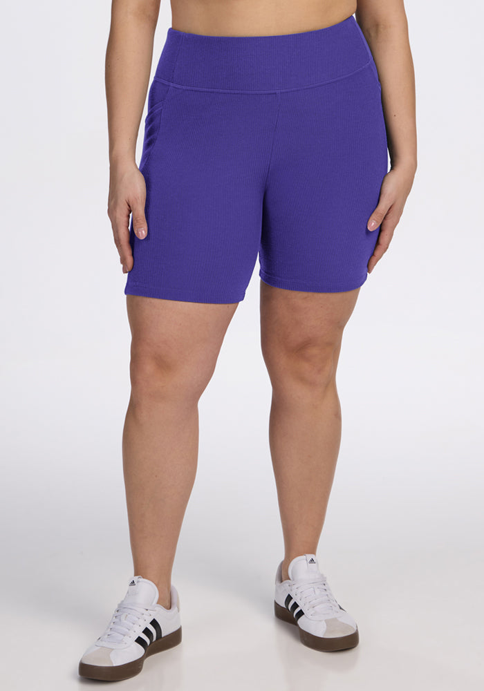 Person wearing Woolx Miley Bike Shorts - Berry Indigo and white sneakers, standing against a plain white background. | Juliana is 5'10", wearing a size XL