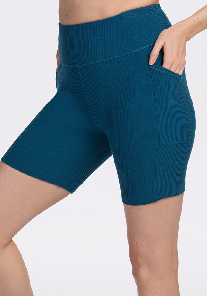 Model wearing Woolx Miley Bike Shorts in Moroccan Blue, hand in pocket, shown waist to mid-thigh. Final sale.