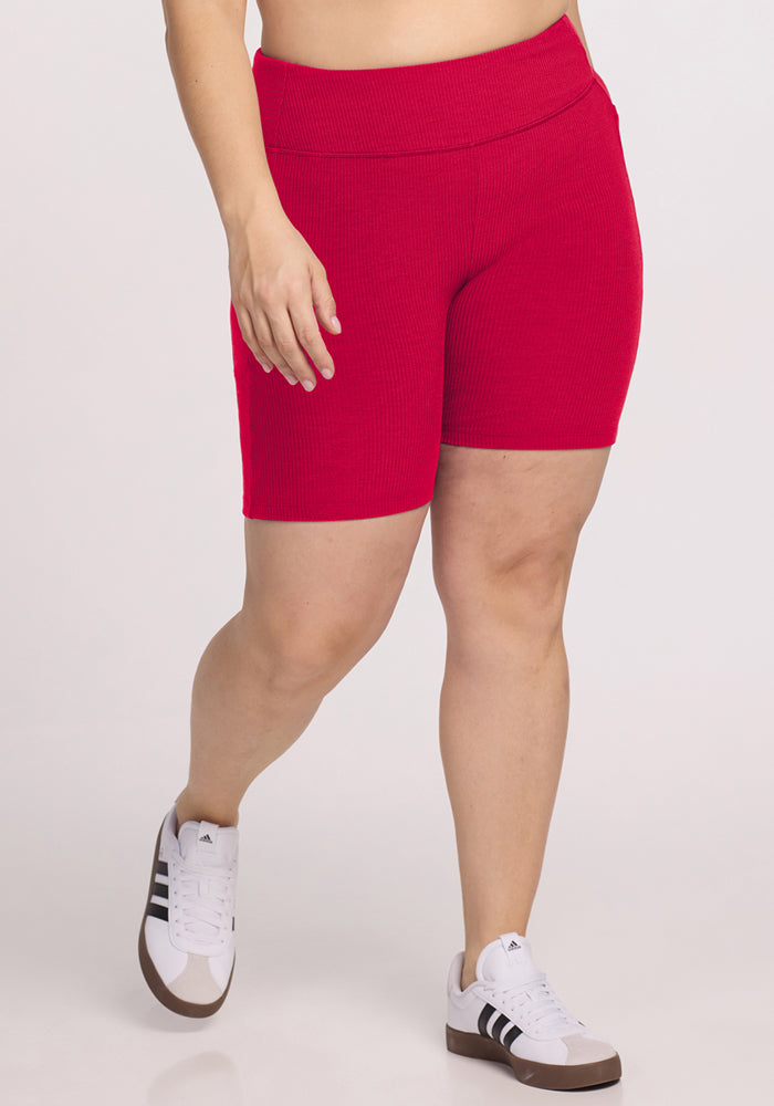 Someone wearing Woolx Miley Bike Shorts in Poppy Spark stands on a plain background.