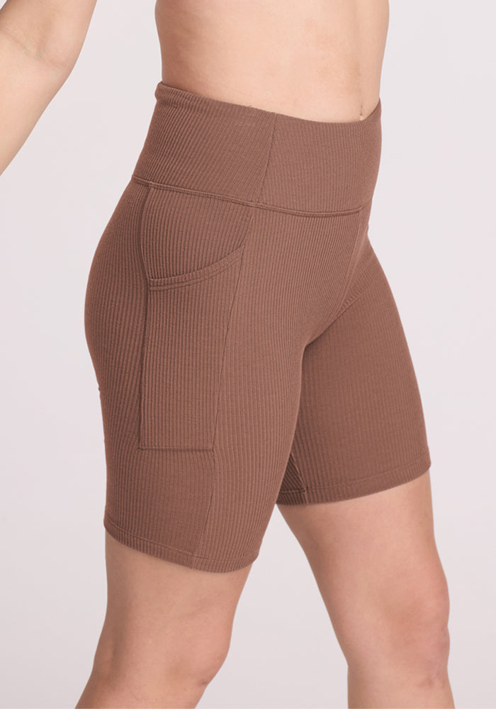 Model wears Woolx Miley Bike Shorts in Sienna Kiss, high-waisted and ribbed, shown mid-torso to mid-thigh.