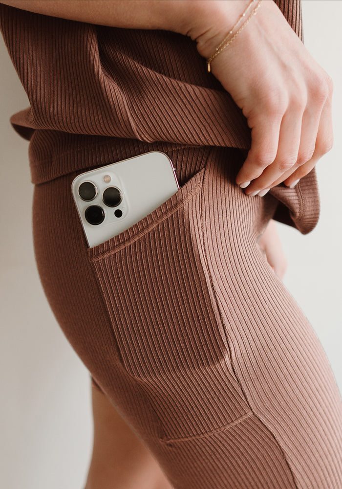 Close-up of a person in Woolx Miley Bike Shorts • Final Sale - Sienna Kiss, phone in pocket, hand resting nearby.