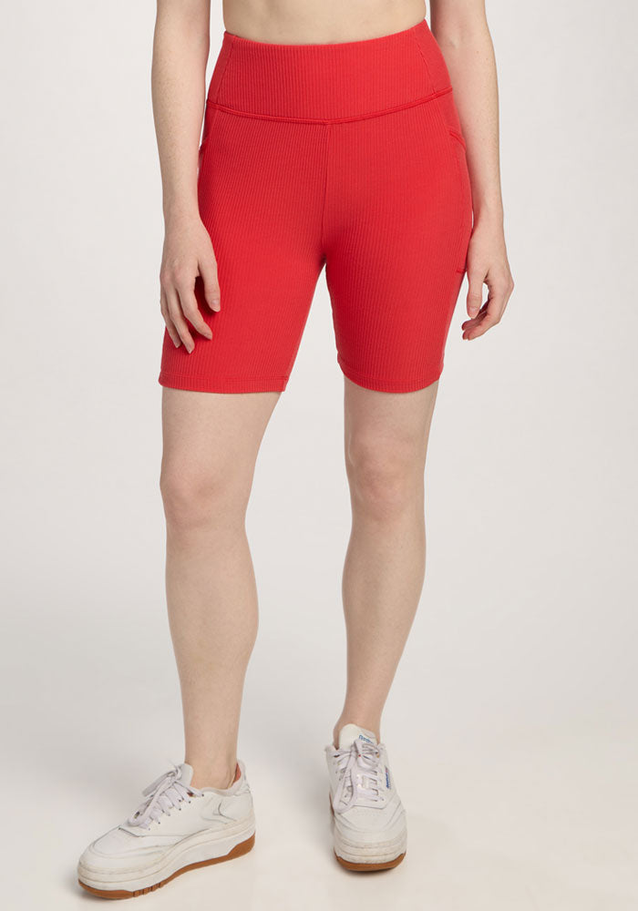 Person wearing Woolx Miley Bike Shorts in Hibiscus and white sneakers, standing against a plain light background. | Shea is 5’9”, wearing a size S