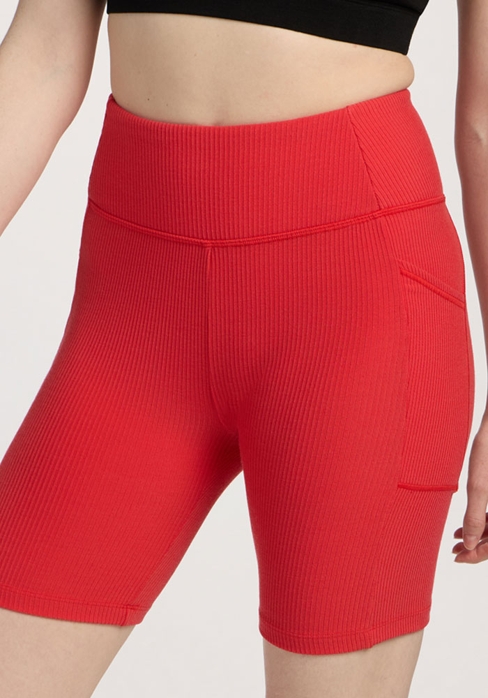 Person wearing Woolx Miley Bike Shorts - Hibiscus, high-waisted with side pocket, and a black crop top.