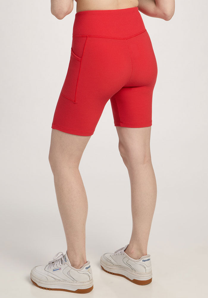 Person wearing Woolx Miley Bike Shorts - Hibiscus with a pocket, white sneakers, against a plain background.