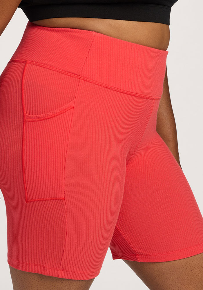 Person wearing Woolx Miley Bike Shorts - Hibiscus with ribbed texture, side pocket, and a black crop top.
