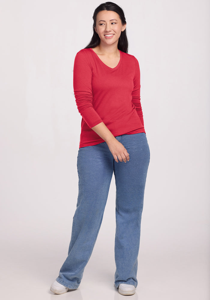 Woman wears the Woolx Millie Long Sleeve in Berry Ice Pop with blue jeans, smiling against a plain light background.
