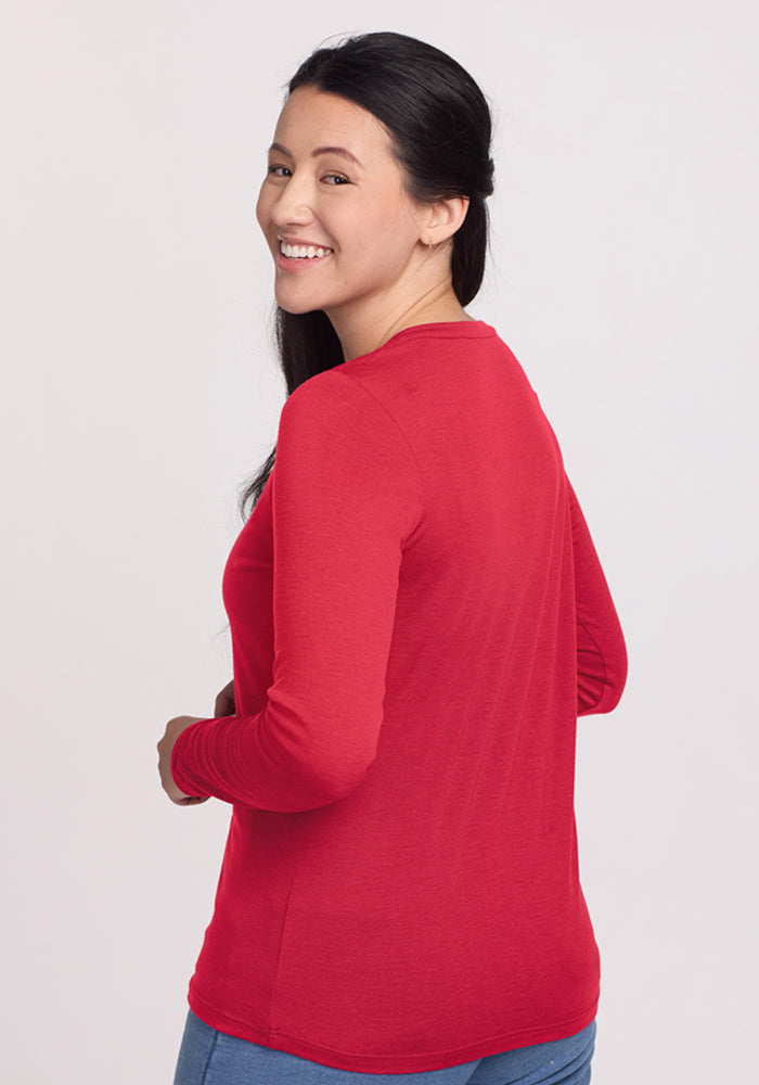 A smiling woman wears the Woolx Millie Long Sleeve in Berry Ice Pop and blue jeans, looking over her shoulder.