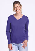 A smiling woman wears the Woolx Millie Long Sleeve in Berry Indigo and light blue jeans against a plain background. | Ariana is 5'11", wearing a size S