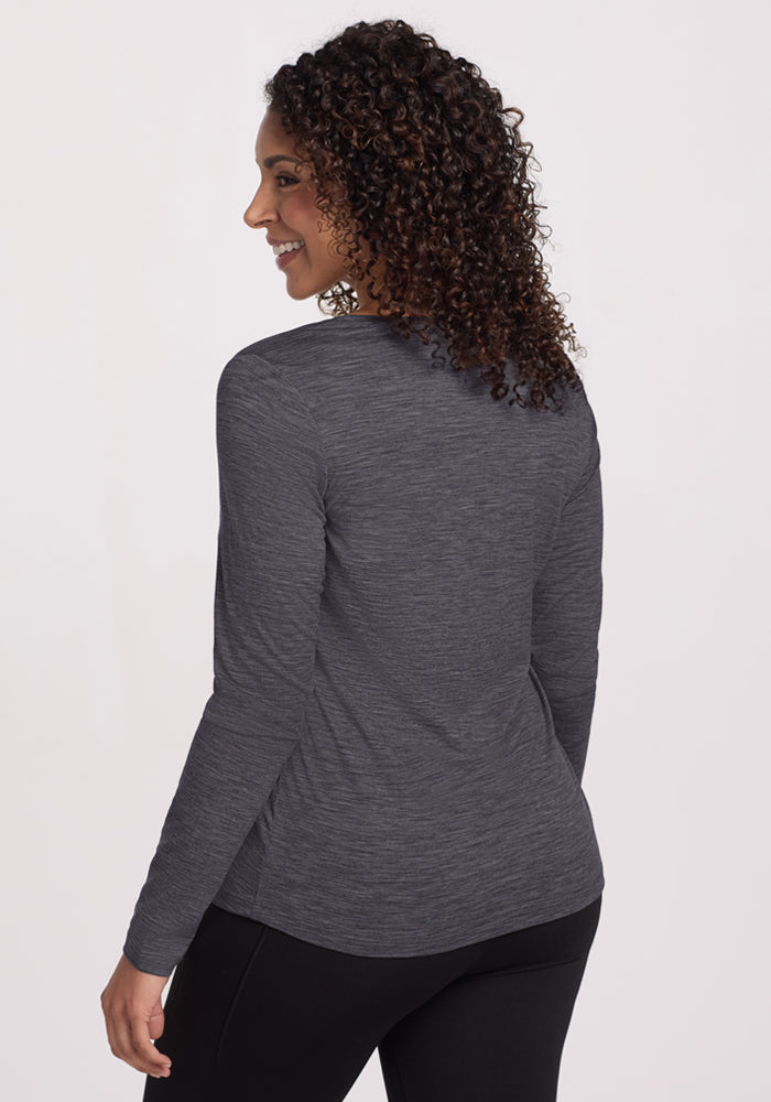 Smiling woman with curly hair, shown from the back, wears Woolx Millie Long Sleeve in Cinder Melange and black pants.