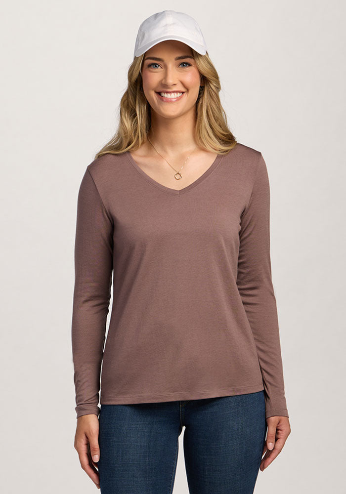 Woman smiling in a Woolx Millie Long Sleeve - Peppercorn, blue jeans, and white cap against a plain background. | Ariana is 5'11", wearing a size S