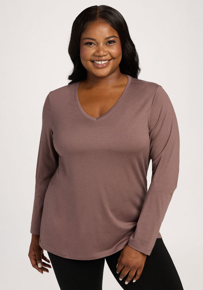 Smiling woman wears the Woolx Millie Long Sleeve in Peppercorn with black pants against a plain light background. | Sapphire is 5’8”, wearing a size XL