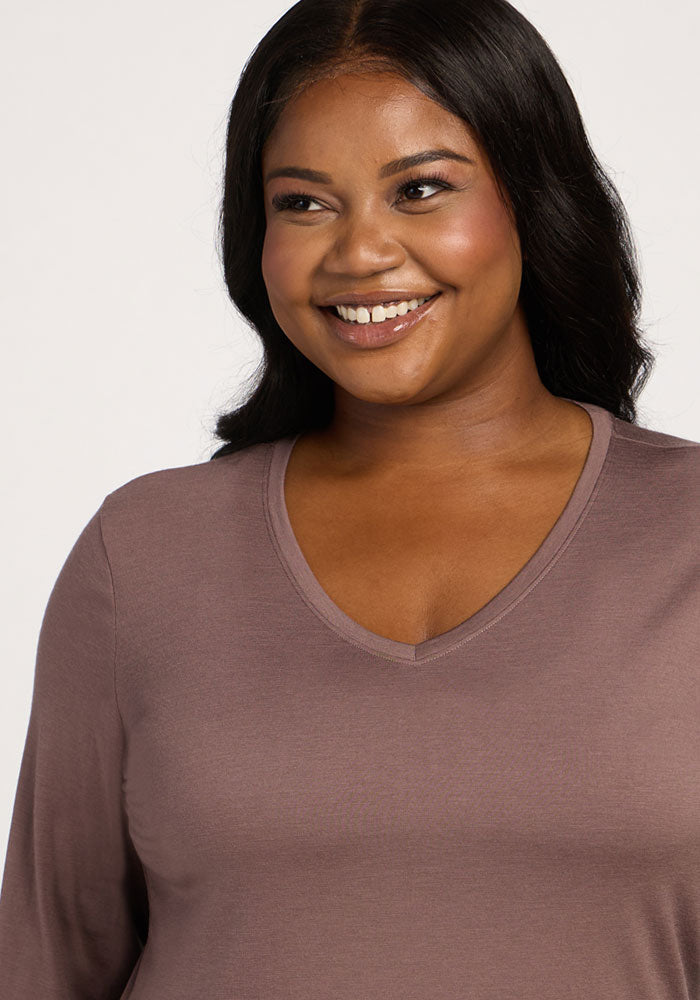 Woman with long, dark hair smiles in the Woolx Millie Long Sleeve - Peppercorn, a temperature-regulating merino wool top.