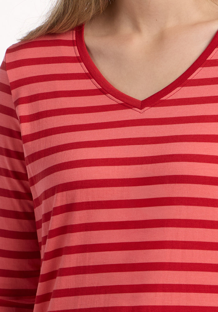 A close-up of someone wearing the Woolx Millie Long Sleeve in Wildberry Stripe shows the upper chest, neck, and part of the left shoulder. This Merino wool shirt is temperature-regulating and moisture-wicking. The person's face is not visible.