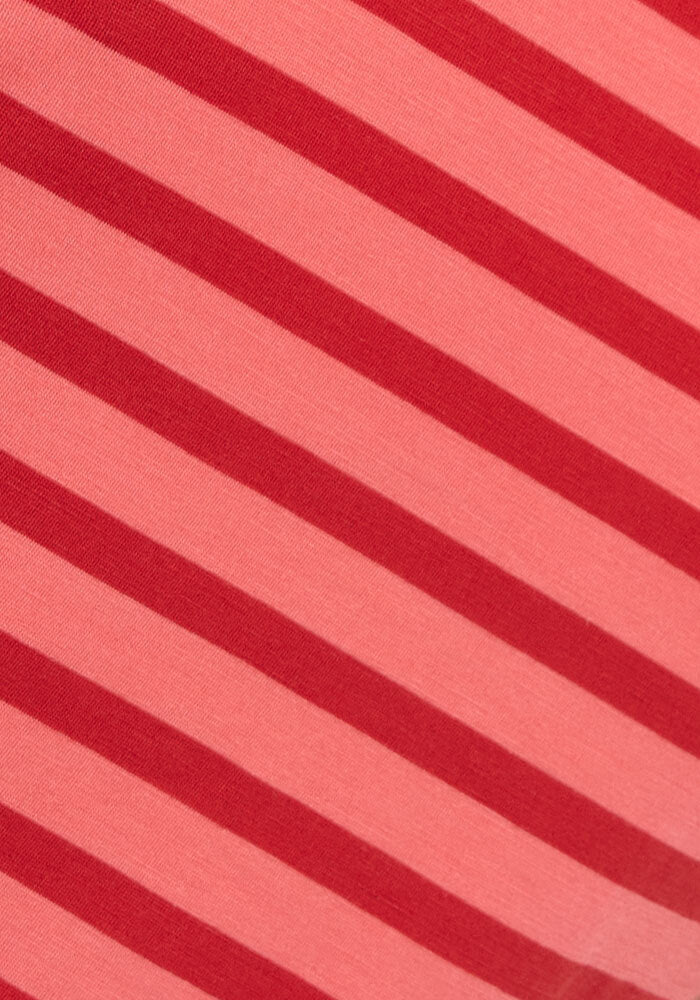 The Woolx Millie Long Sleeve - Wildberry Stripe features diagonal red and pink stripes in alternating thick and thin lines across soft Merino wool, highlighting its textured fabric, visible stitch lines, and moisture-wicking properties.