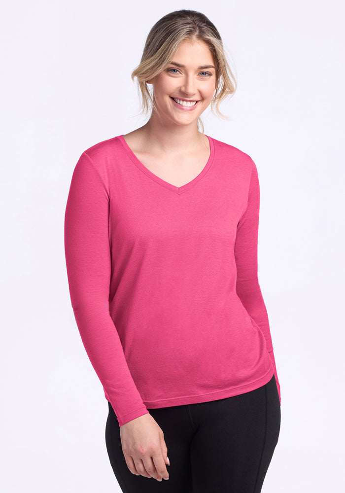 Smiling woman in Woolx Millie Long Sleeve - Raspberry Fizz & black pants, standing against a light background.