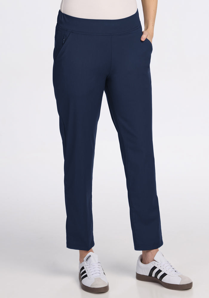 A person wears Woolx Nicole Ankle Pants in Deep Navy, paired with white sneakers featuring black stripes, standing against a plain white background. | Jessica is 5’10”, wearing a size S