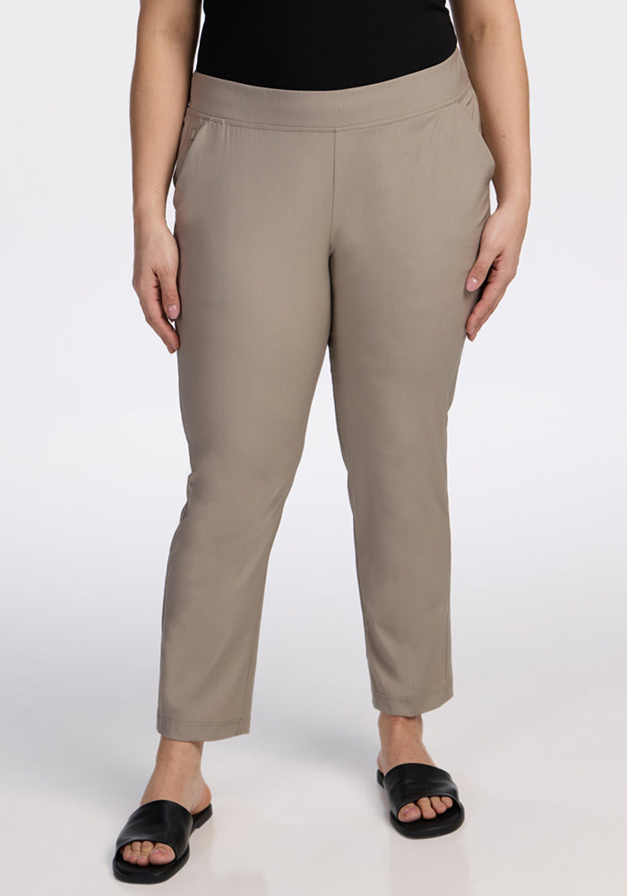 A person wears Woolx Nicole Ankle Pants in Vintage Khaki with black slide sandals, standing against a plain white background. The upper body is cropped out of the image. | Juliana is 5'10", wearing a size XL