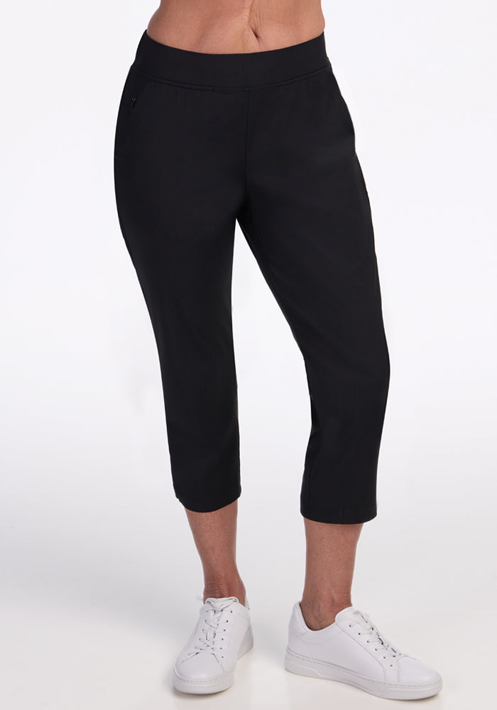 A person models the Woolx Nicole Crop Pants in black with white sneakers, standing against a plain white background. The image is cropped at the waist and below the ankles. | Tam is 5’8.5”, wearing a size S