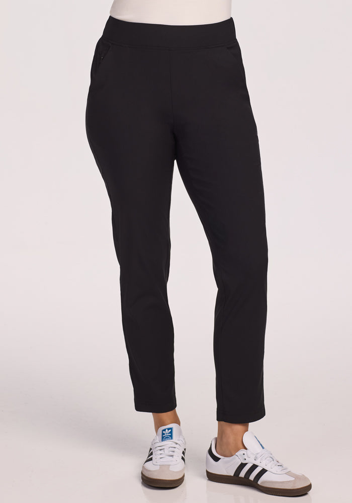 Someone stands against a plain light background, wearing Woolx Nicole Petite Ankle Pant in black. Their upper body is mostly out of frame.