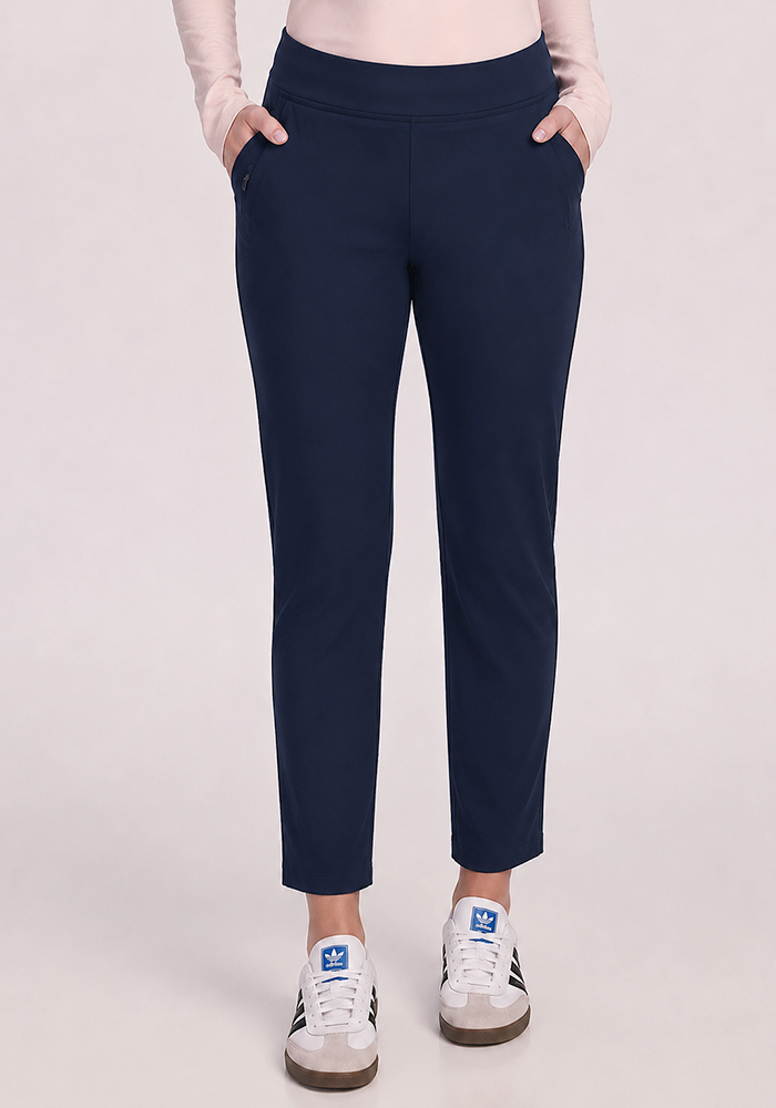 Person wears Woolx Nicole Petite Ankle Pant in Deep Navy and white sneakers with blue logo, against light background.
