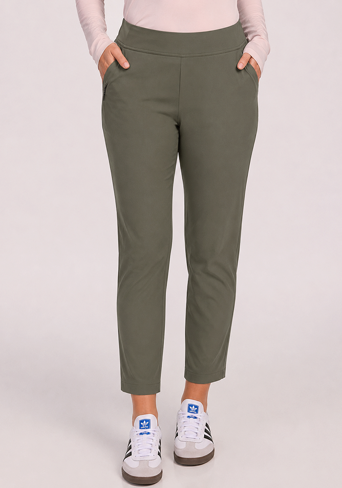 Person wearing Woolx Nicole Petite Ankle Pant in sage olive, pink long-sleeve top, and white Adidas sneakers.