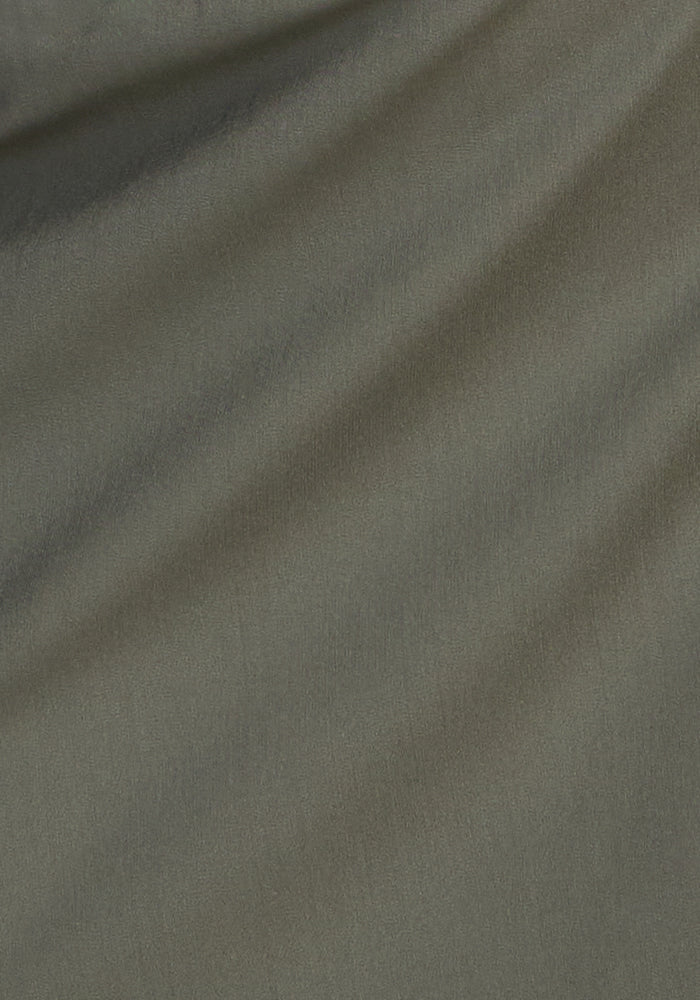 Close-up of sage olive fabric with soft folds and subtle shadows, highlighting the smooth texture and diagonal drape—perfect for the Woolx Nicole Tall Ankle Pant, designed for a refined look and moisture-wicking comfort.