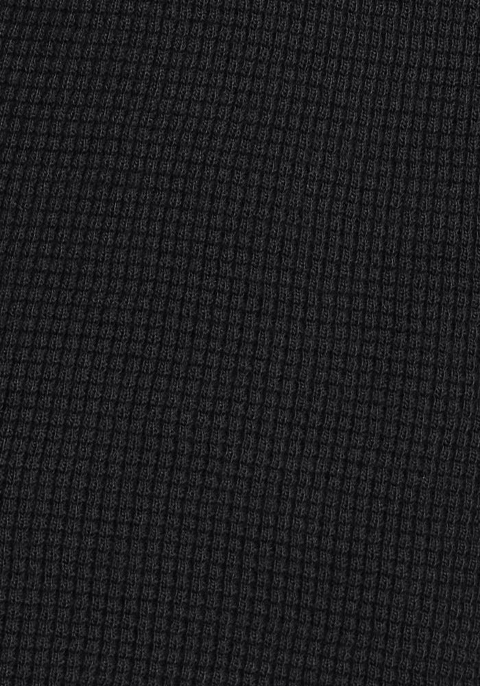Close-up of the Woolx Oaklynn Waffle Shacket in black, featuring ribbed fabric with a waffle-knit texture and raised square grid—perfect as a warm layering shirt.