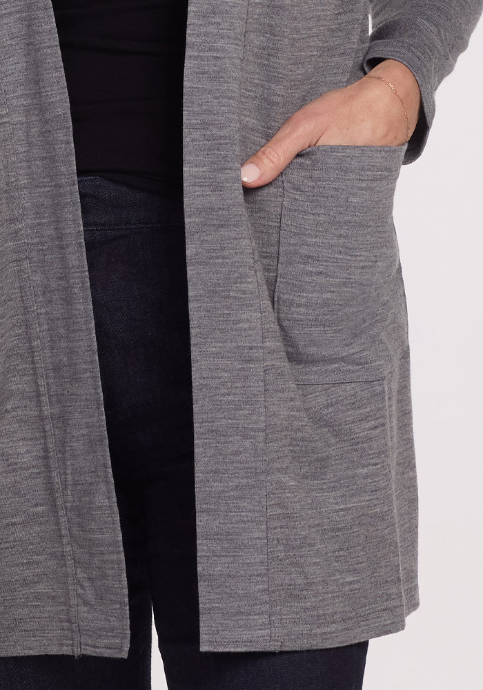 A person in a Woolx Paisley Cardigan - Graphite Heather and dark jeans slips their left hand into the cardigan's pocket. The material feels smooth, offering feather-light comfort as their arm bends slightly at the elbow.