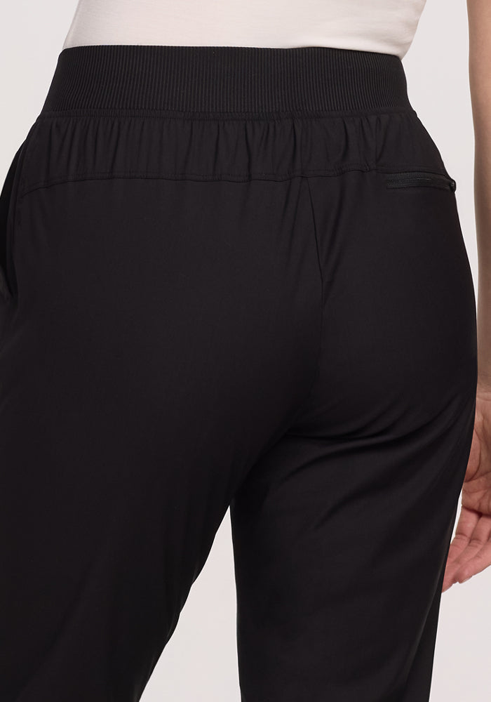 A person wearing Woolx Palmer Joggers - Black, featuring a visible back pocket and an elastic waistband, standing against a plain background.