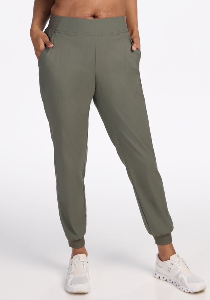 Wearing Woolx Palmer Joggers in Sage Olive with pockets and a fitted waistband, paired with white sneakers. Only the lower half of the body is visible against a plain white background. | Jade is 5’10”, wearing a size S
